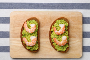 sandwich with shrimp and avocado on wood. breakfast concept