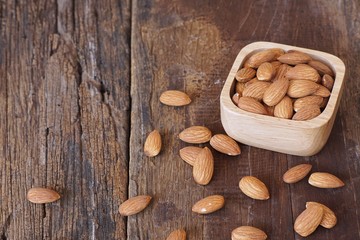 Almond nut in wooden bowl on classic wooden table background