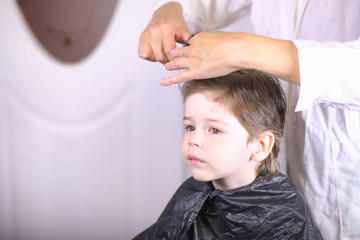 Obraz na płótnie Canvas Hairdresser and boy. The boy is doing his hair. Cut hair child in the hairdresser.