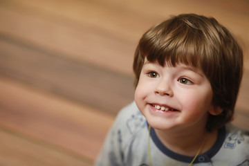 Portrait of a small curly-haired boy. A child wrapped in a rug eats an apple. A two-year-old boy hides under a blanket.