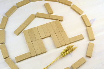 the house is assembled on a wooden surface of rectangular bars next to a dry spikelet