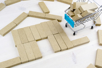 house of wooden beams assembled on a wooden surface next to the house trolley from the supermarket which are bars