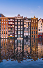 Fototapeta na wymiar Front view of beautiful colorful traditional Amsterdam houses on the Amstel river bank reflecting in the river. Traditional dutch architecture
