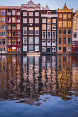 Front view of beautiful colorful traditional Amsterdam houses on the Amstel river bank reflecting in the river. Traditional dutch architecture