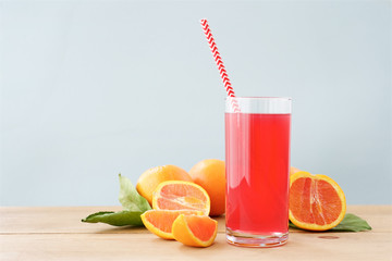 Glass of fresh orange juice on wooden table. Red color of orange juice. Light Mint Background