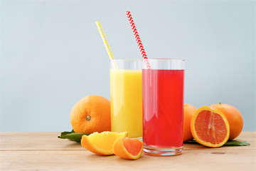 Glass of fresh orange juice on wooden table. Red and orange colors of orange juice. Light Mint Background