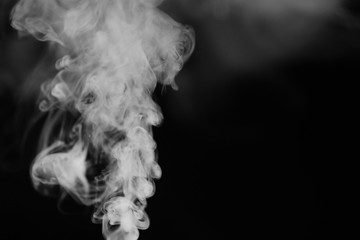 White smoke on a black background. Texture of smoke. Clubs of white smoke on a dark background for an overlay