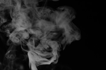 White smoke on a black background. Texture of smoke. Clubs of white smoke on a dark background for an overlay