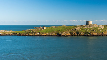 Fototapeta na wymiar Uninhabited green small island in the Irish Sea with a derelict church and an abandoned defensive fort also known as a Martello Tower. Dalkey Island in Dublin, Ireland.