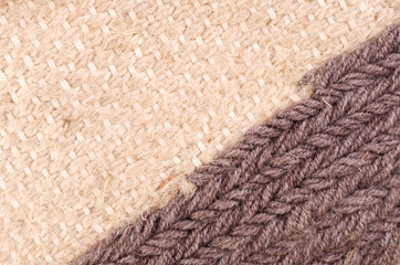 Vertical fragment of tapestry with wool threads in warm colors. Fabric texture with braided thread. Colored background with close up of a traditional beautiful textile. Craft carpet texture.
