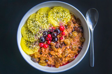 Breakfast oatmeal porridge with cinnamon, cranberries and blueberries, front view, selective focus