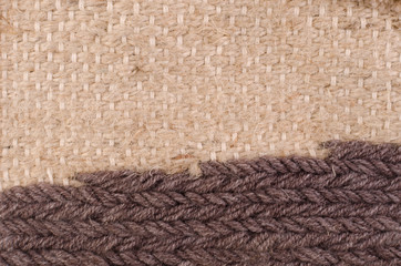 Horizontal fragment of tapestry with wool threads in warm colors. Fabric texture with braided thread. Colored background with close up of a traditional beautiful textile. Craft carpet texture.