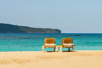 Beautiful tropical beach with two yellow sun beds and amazing turquoise colored seawater. Perfect vacation destination in Las Galeras in Dominican Republic.