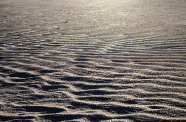 Close up of a wavy, ondulated sandy beach: silver sand, nobody around