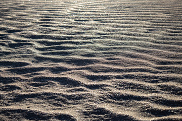 Close up of a wavy, ondulated sandy beach: silver sand, nobody around