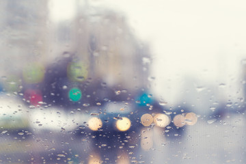 Blurred view through the windshield of a car with raindrops at a crossroad and pedestrian crossing.