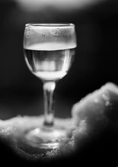 Glass wineglass with liquid standing on the snow with a blurred background