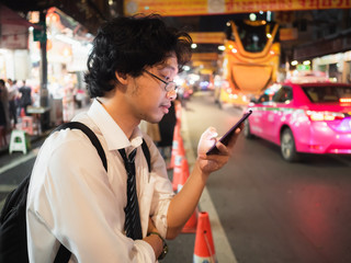 Young Asian business man using mobile smart phone in the street at night. Social and internet of thing concept.