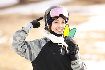 初心者マークを持ちヘルメットを指さすスノーボードウェアの女性