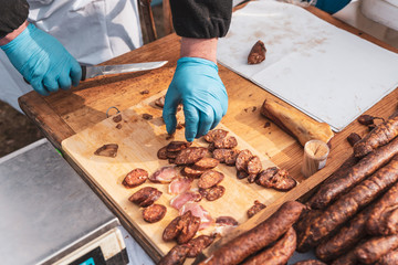 men's hands with gloves chop with a knife of a piece of sausage