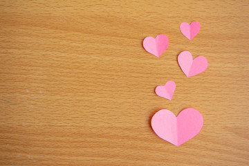 Pink paper cut of mini heart on brown wood background,love valentine concept, minimal top view flat lay.