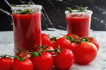 Tomato juice garnished with a rosemary branch and fresh ripe red cherry tomatoes