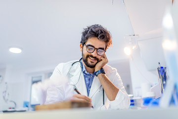 Male Doctor Writing On Medical Document
