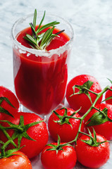 Tomato juice garnished with a rosemary branch and fresh ripe red cherry tomatoes
