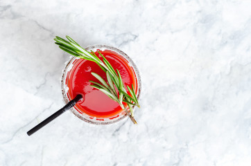 Fototapeta na wymiar Tomato juice garnished with a rosemary branch on a marble background