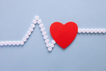 medicine, healthcare and pharmacy concept - pills and of drugs in shape of the heart and heart rhythms.