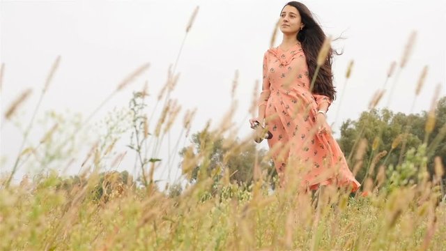 Beautiful girl walks in the field. In the hands of the camera. Slow motion