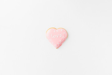 Heart shape cookie with love sign on white textured background