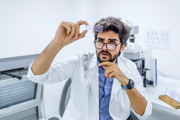 Male scientist examining microscope slide in medical lab