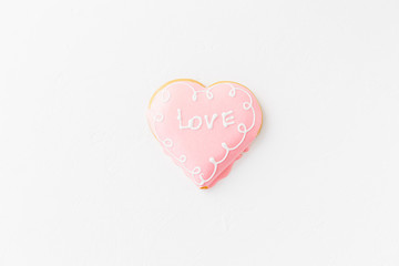 Heart shape cookie with love sign on white textured background
