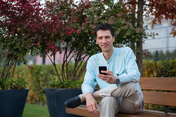 Fototapeta premium Handsome man using his mobile phone in a park