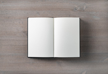 Opened blank book mock up on wood table background. Flat lay.