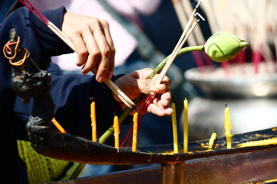 Hand take a fired joss stick with caddle light in temple of Thailand