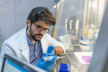 Young male scientist using auto-pipette with flask in medical science laboratory. Researcher concept.