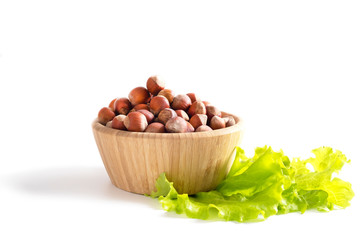 Hazelnuts in wooden bowl and green salad leaves. concept of diet. Isolated on white background