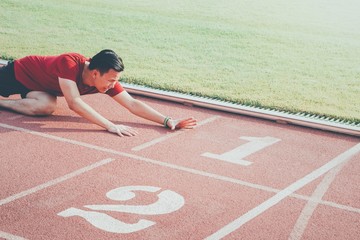 Asian athletes sport man falls down and reaches the finish line on running track while...