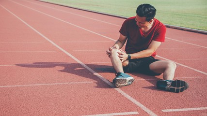Asian athletes sport man resting on running track with knee injury after exercising.Concept of people hard work with sport activity.