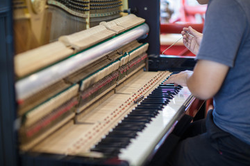 Musician or technician tuning piano using lever and tools