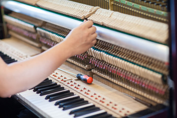 Musician or technician tuning piano using lever and tools
