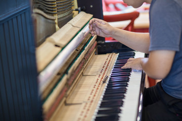 Musician or technician tuning piano using lever and tools