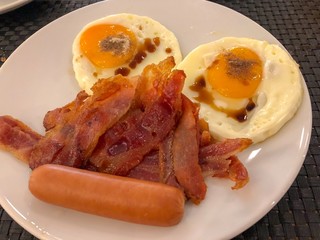 American breakfast with fried fresh eggs and crispy fried bacons in white plate