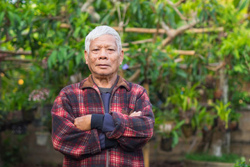 Portrait of elderly man standing in home garden.