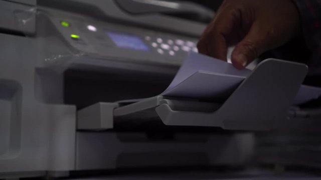Business office Concept : Hand person employed press button on panel of printer for process paperwork on laser print cartridge, lay down or take papers from laser copy machine at Busy Offices.