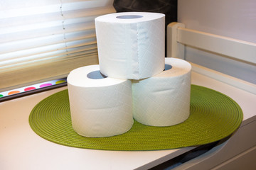 3 rolls stacked toilet paper on a green underground in a bathroom