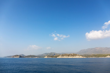 Fototapeta premium Mediterranean sea overlooking the mountains. Aerial top view of sea waves hitting rocks on the beach with turquoise sea water. Amazing rock cliff seascape in the coastline.