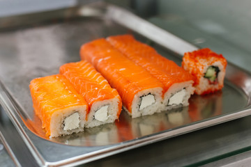 Sushi roll japanese food in shop. California Sushi roll set with salmon, cream cheese, flying fish roe and caviar closeup. Japan restaurant menu